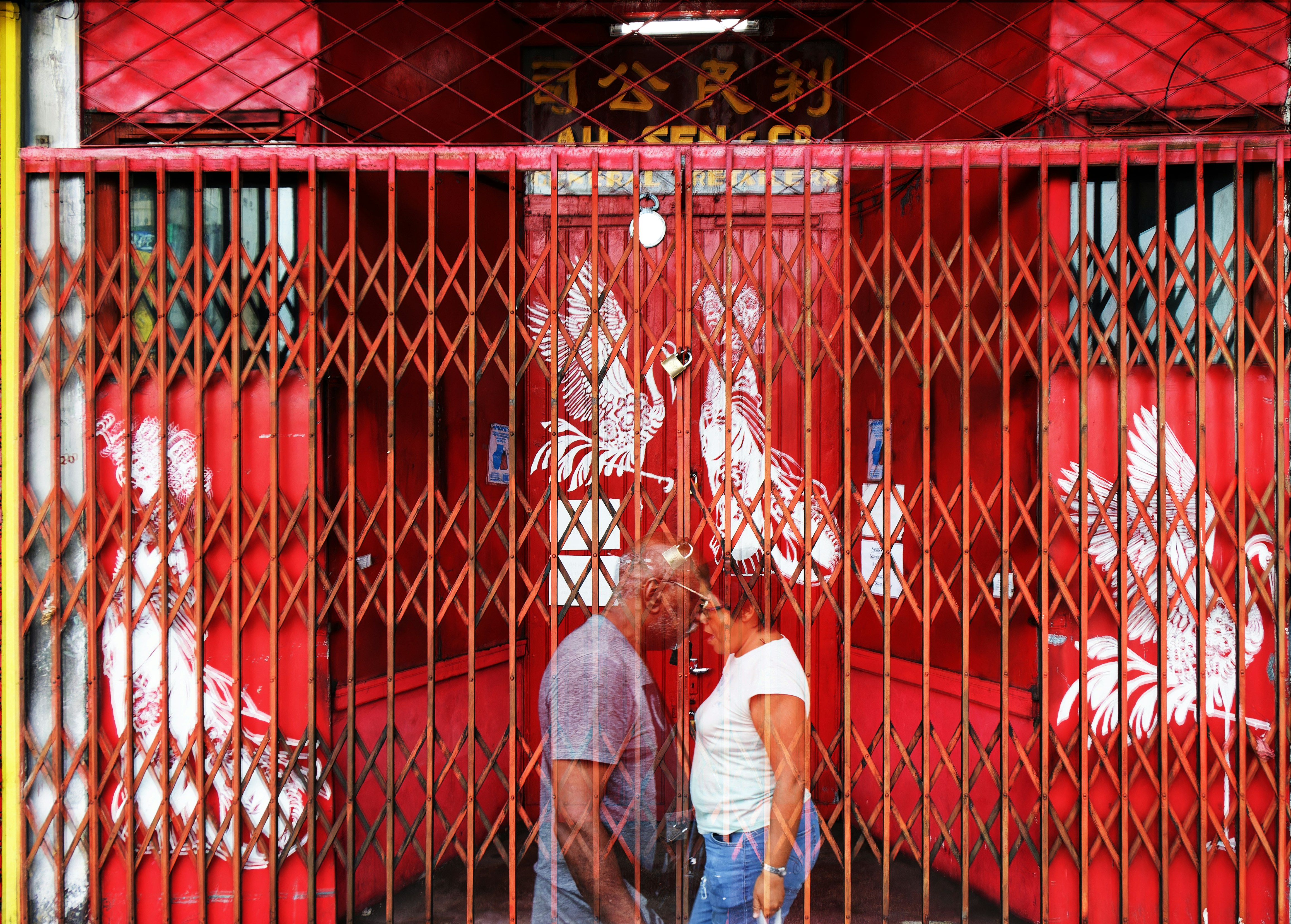 a man and a woman standing in front of a red fence