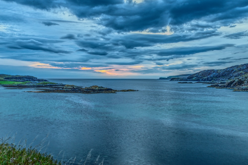 a large body of water surrounded by a lush green hillside