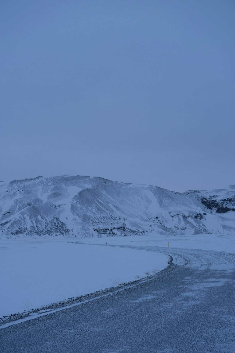 a snowy road with a mountain in the background