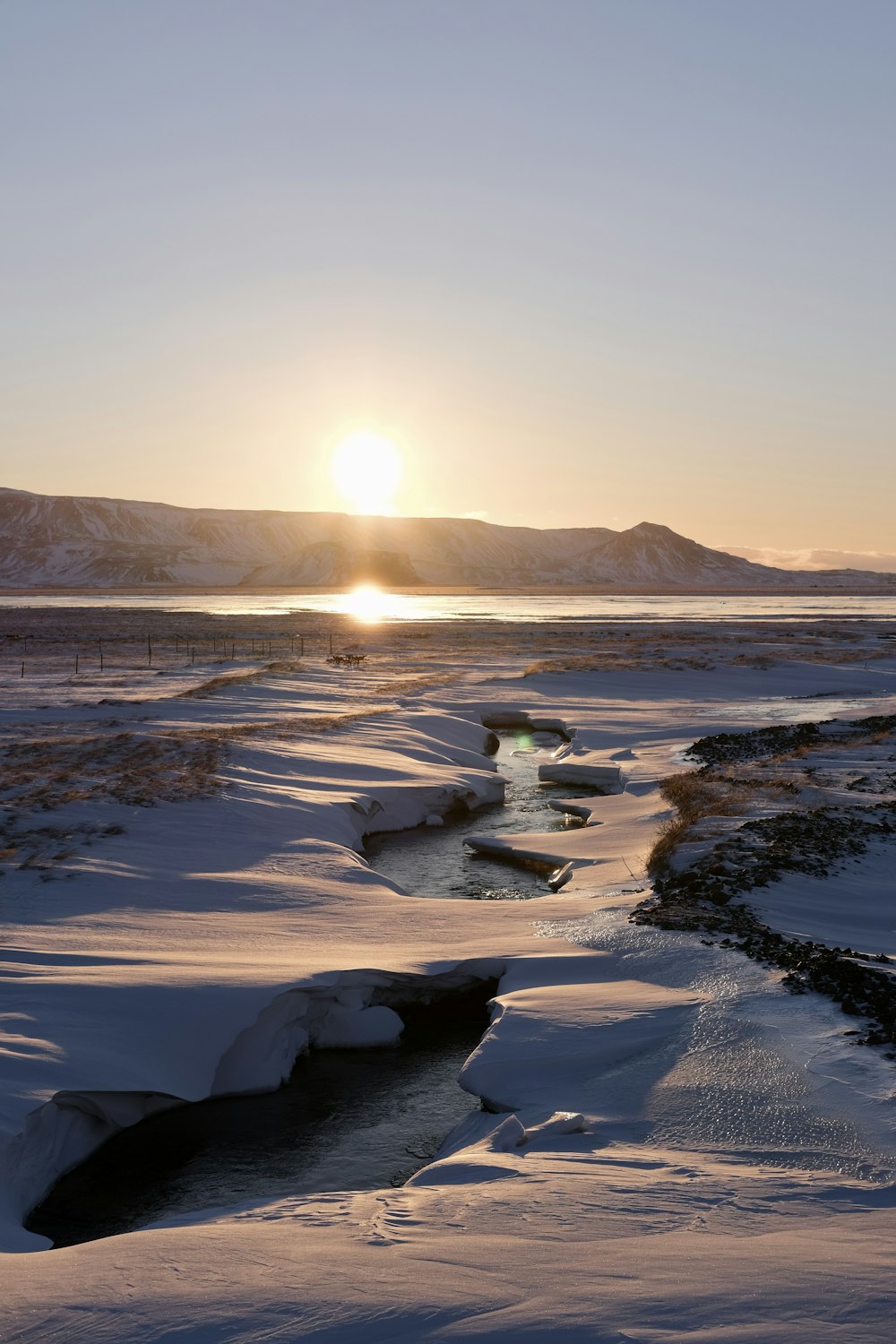 the sun is setting over a snowy landscape