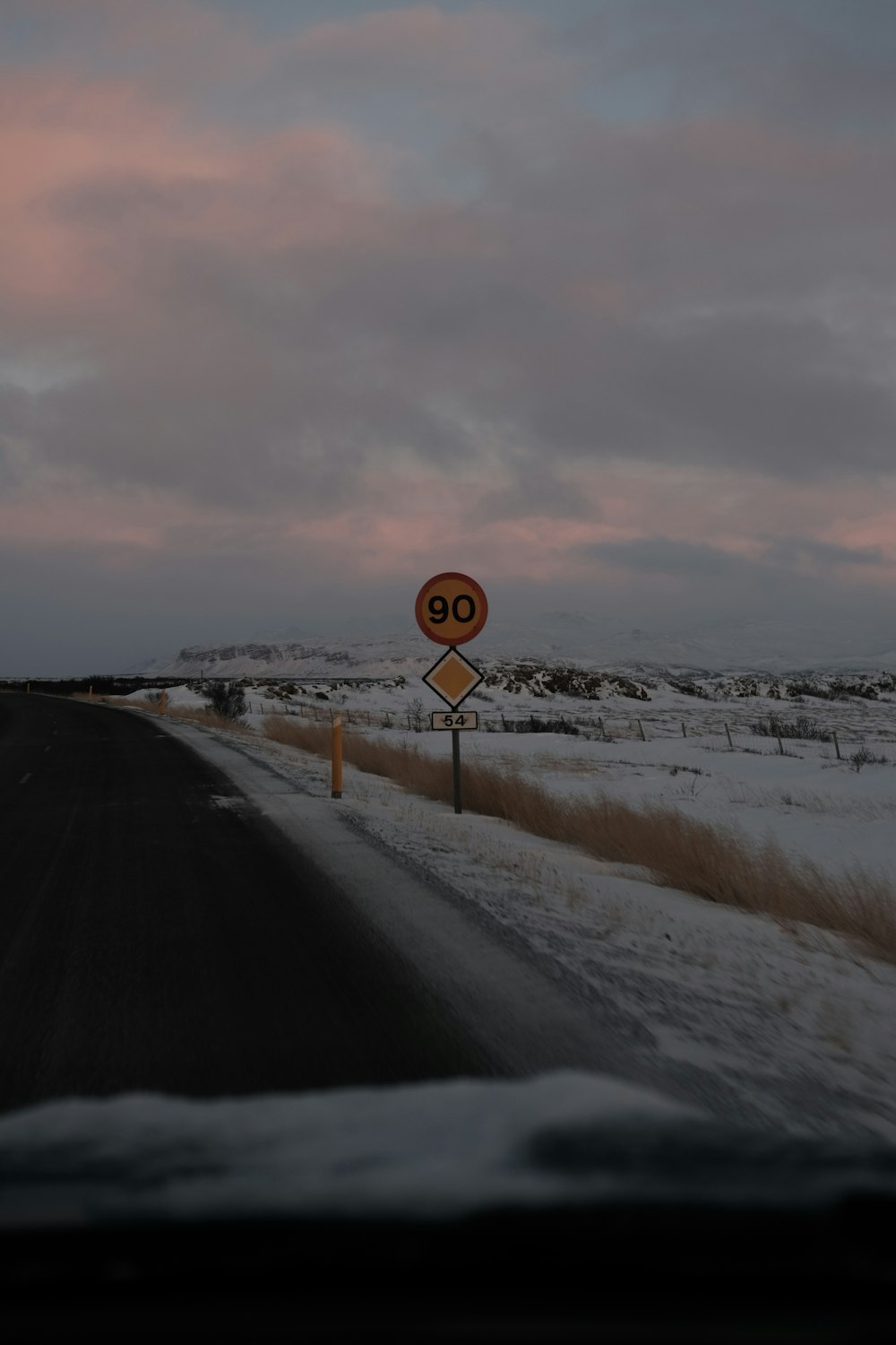 a speed limit sign on the side of a snowy road