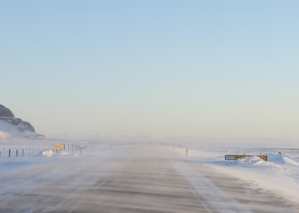 a snow covered road with a mountain in the background