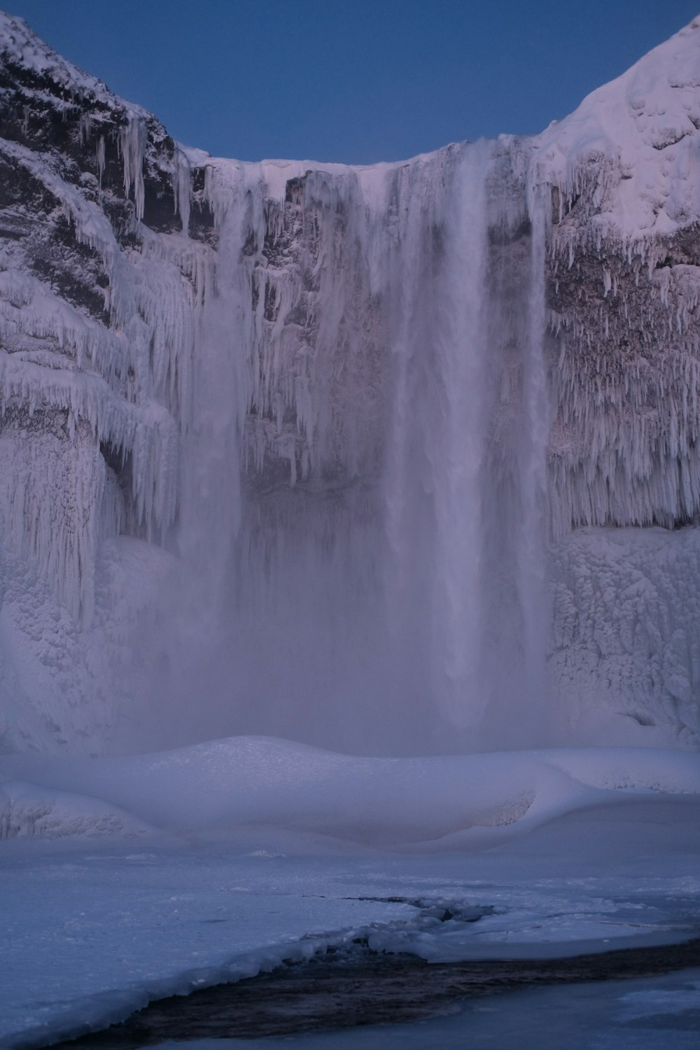 a large waterfall with ice hanging off of it's sides