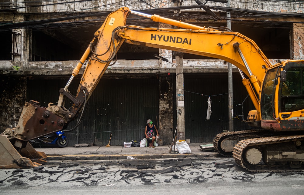 a large yellow excavator sitting in front of a building