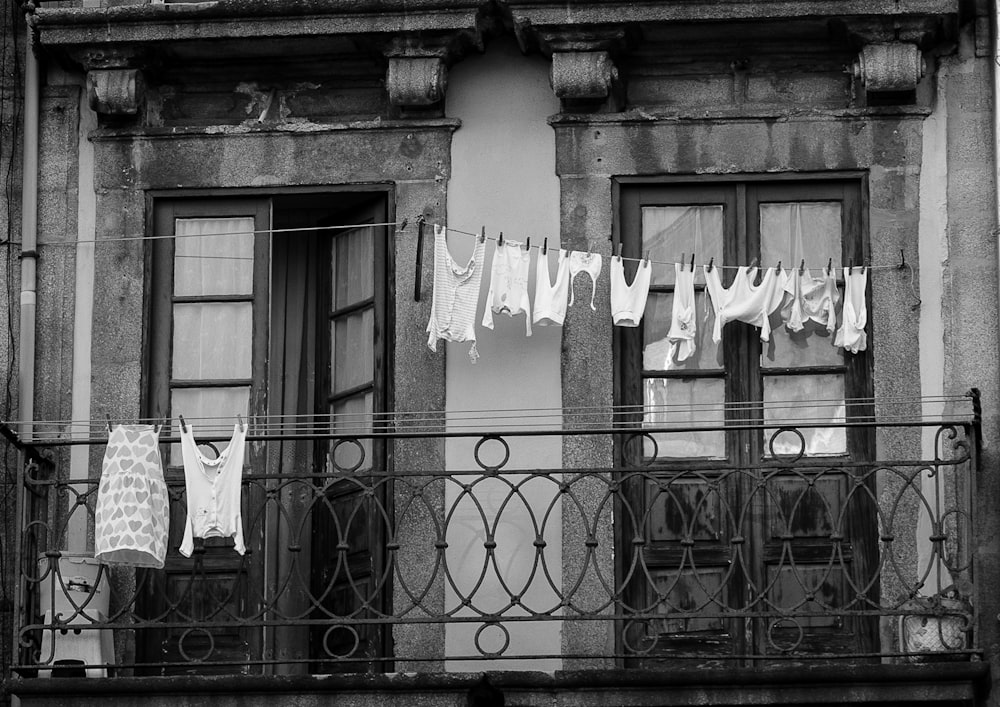 a black and white photo of clothes hanging on a balcony