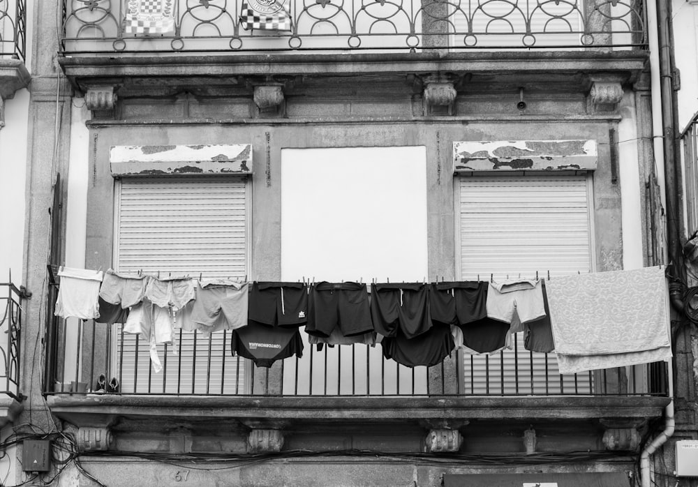 a black and white photo of clothes hanging on a balcony