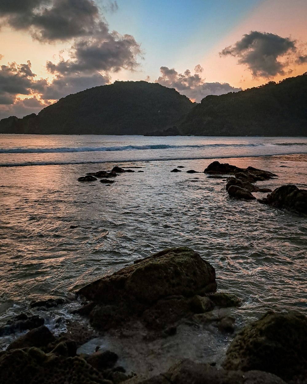 a body of water sitting next to a lush green hillside