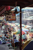 a group of people sitting under umbrellas in a market