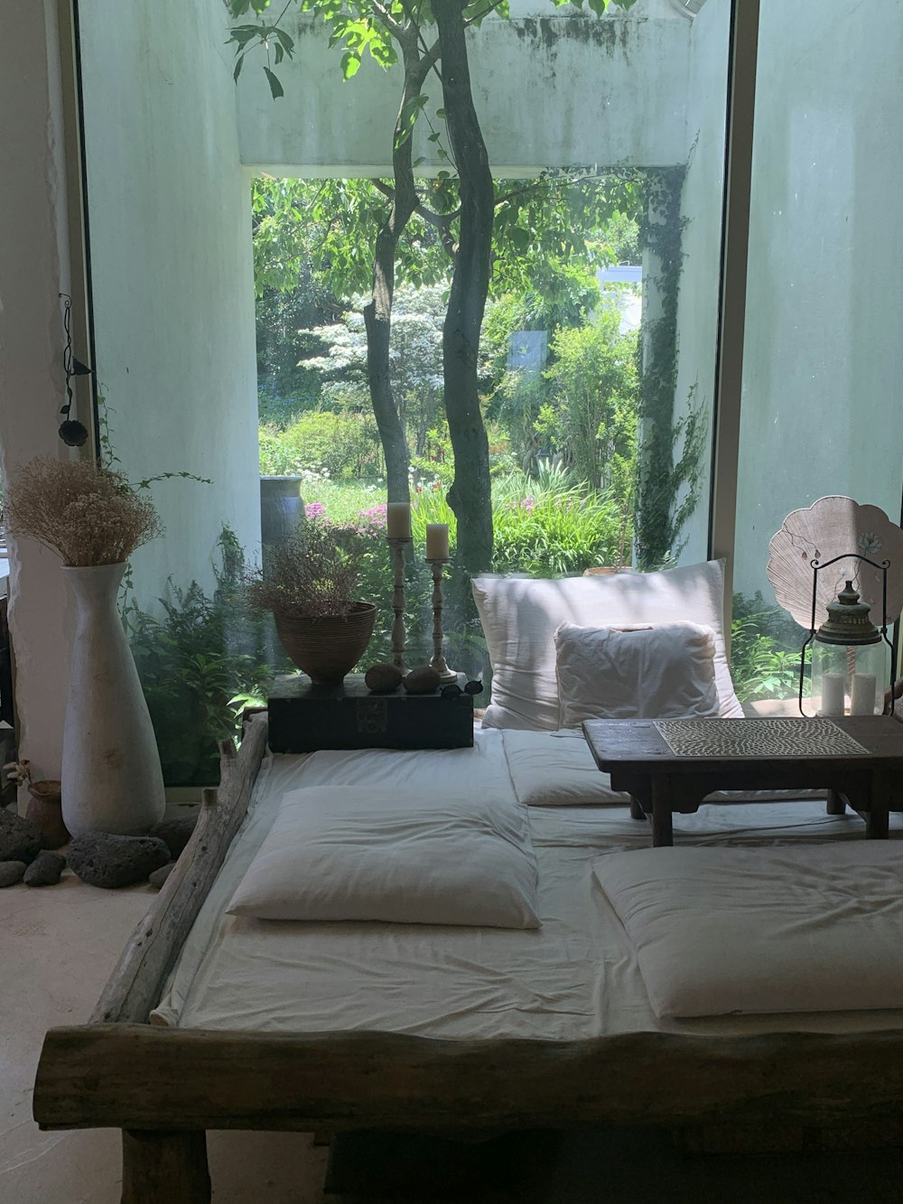 a room with a large window and a bed with white sheets