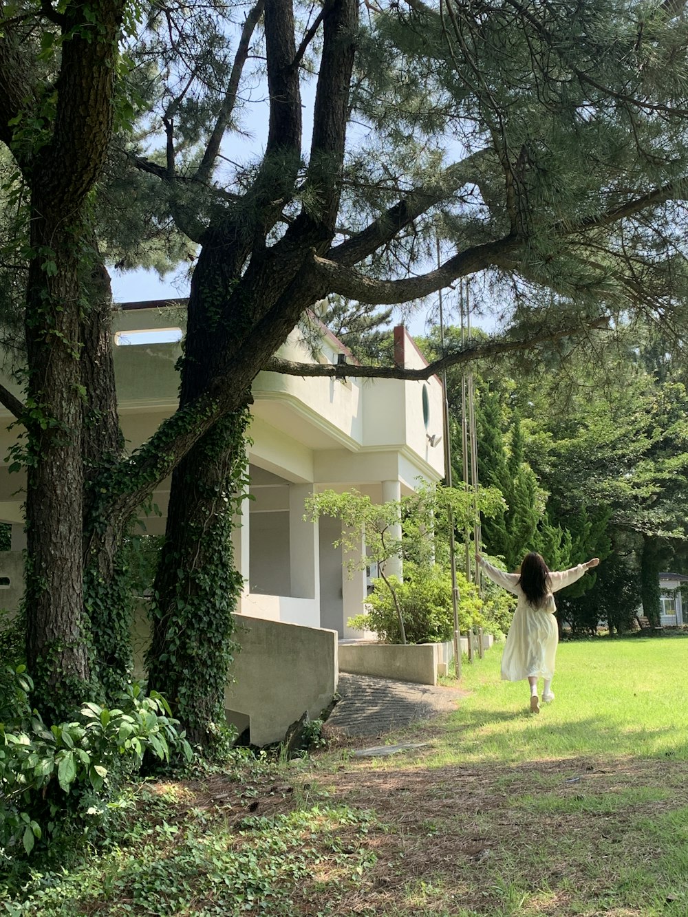 a woman in a white dress is walking through the grass