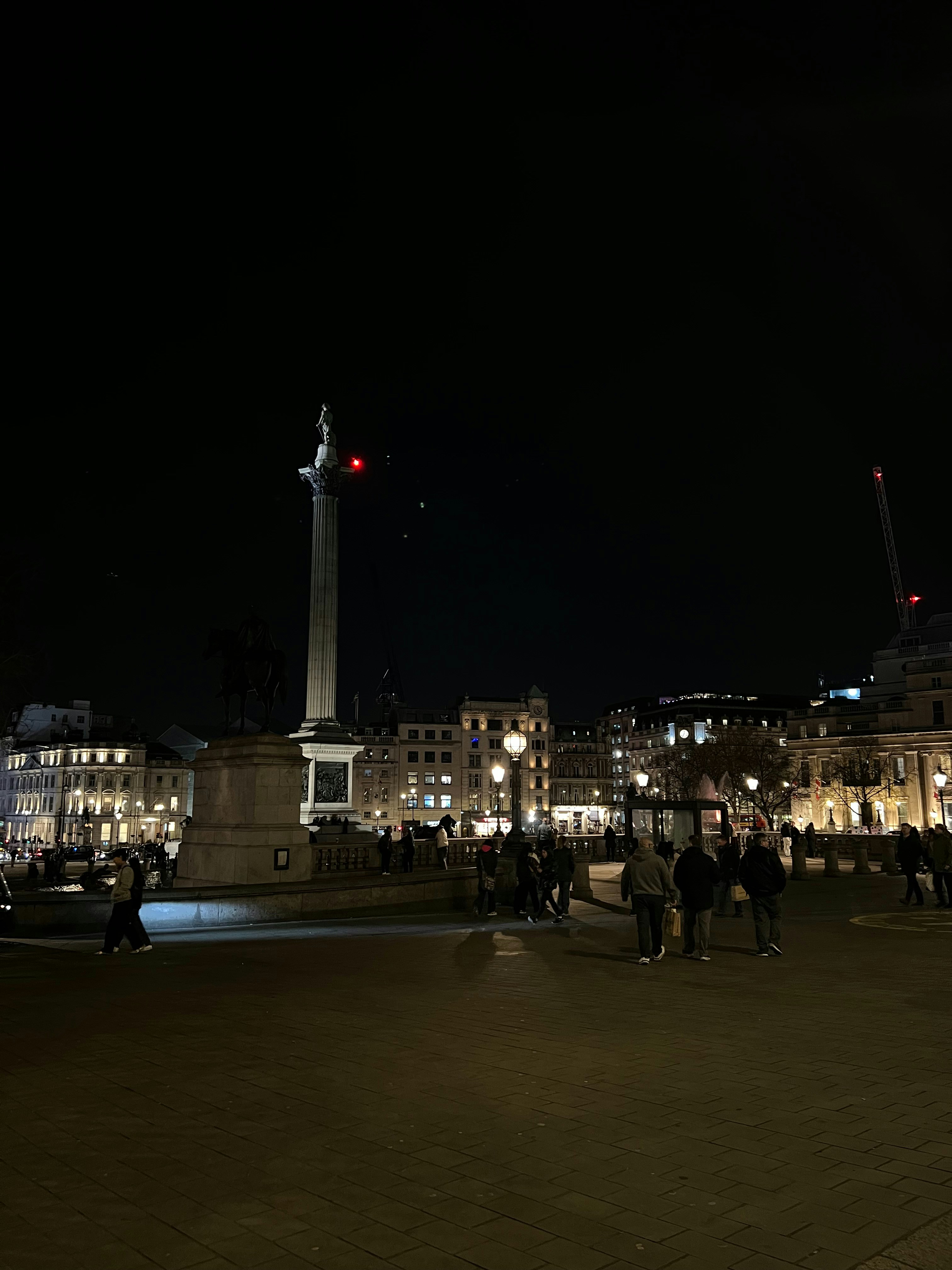 a group of people walking around a city at night