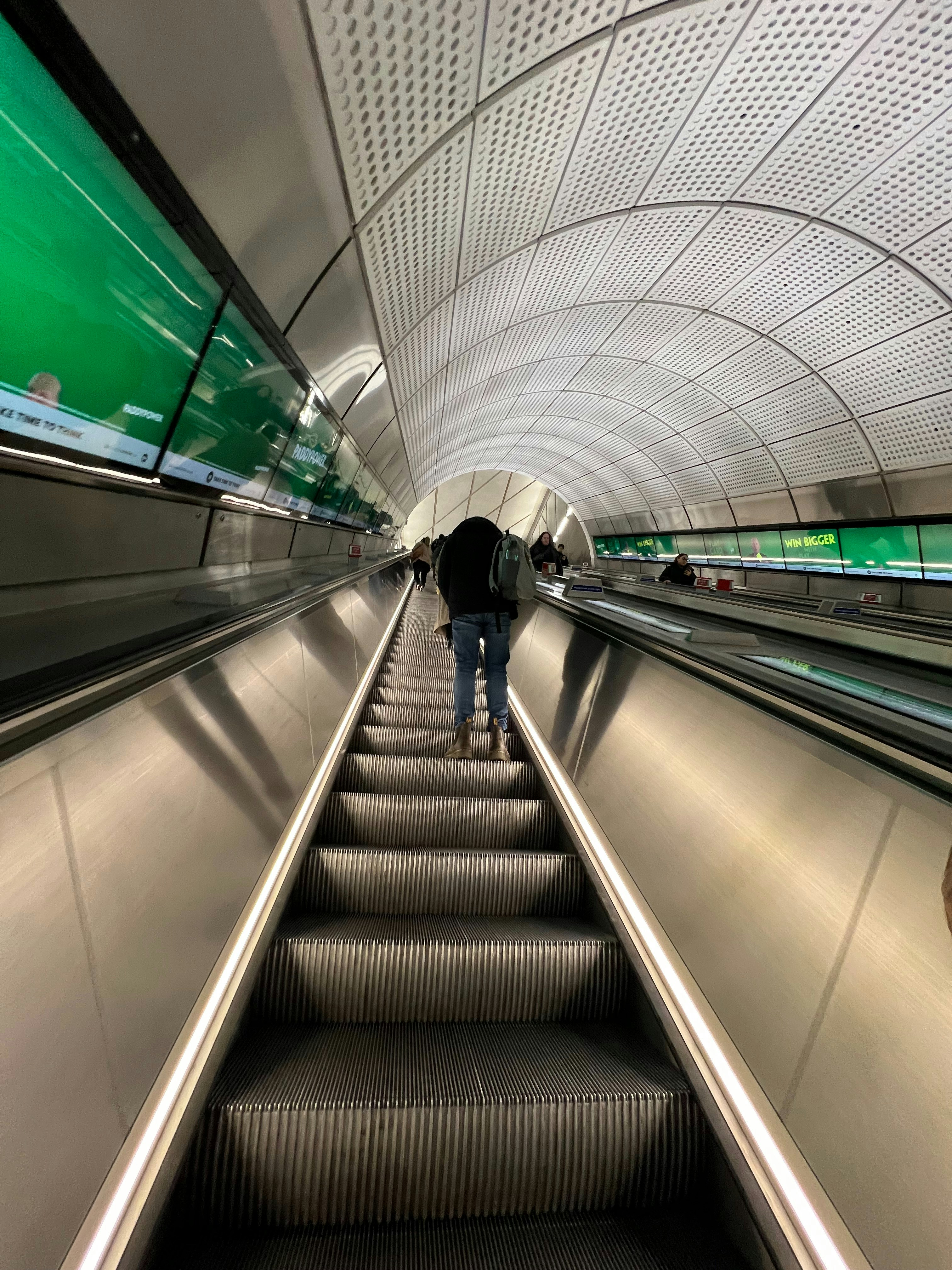 a man walking down an escalator with an umbrella