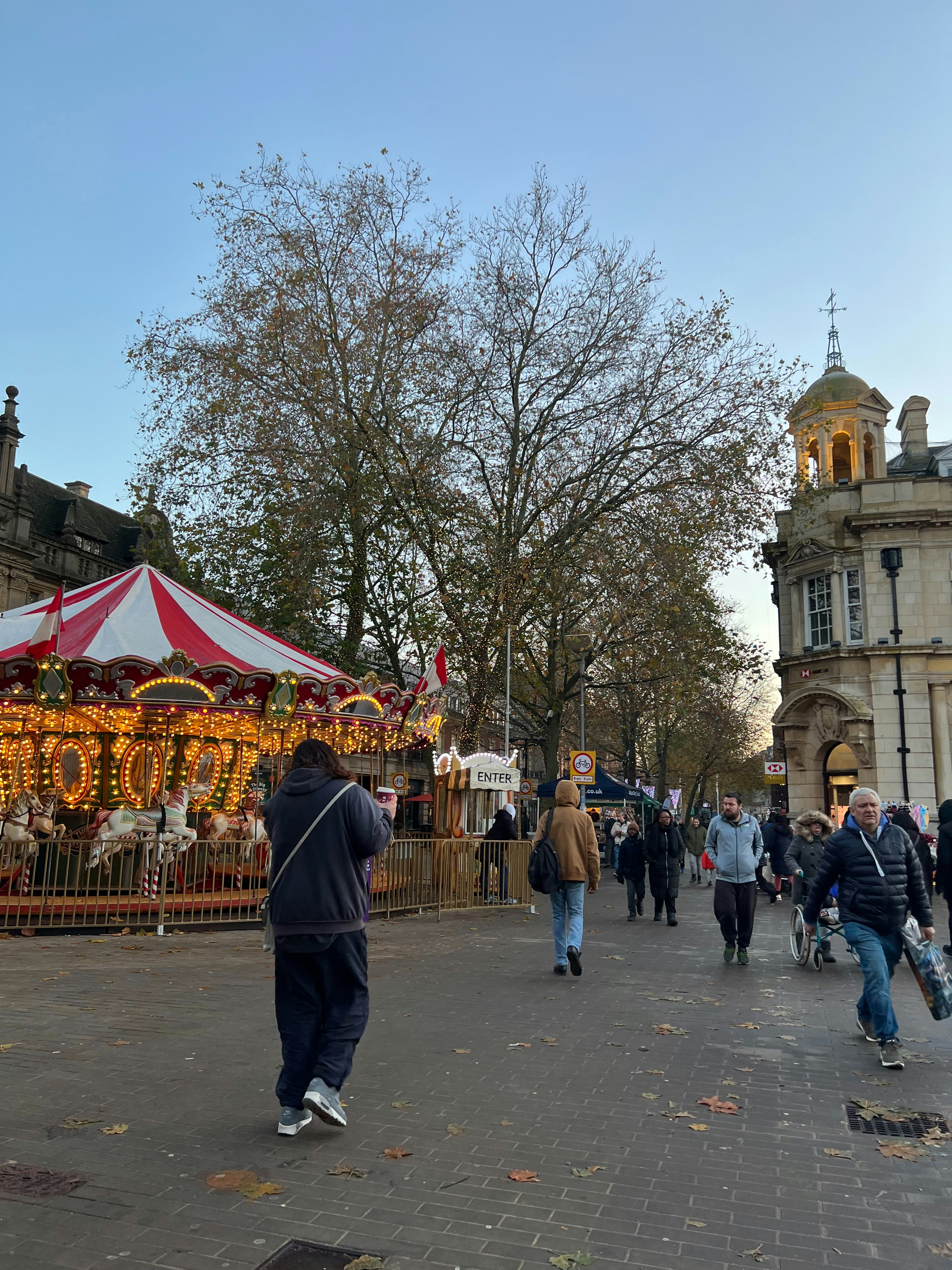 a group of people walking down a street next to a carousel
