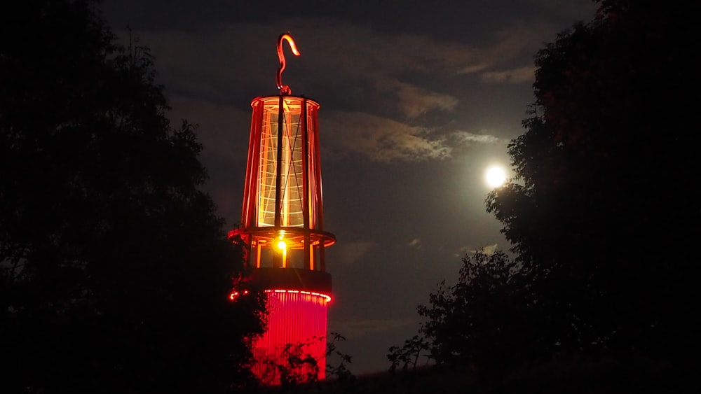 a clock tower lit up at night with the moon in the background