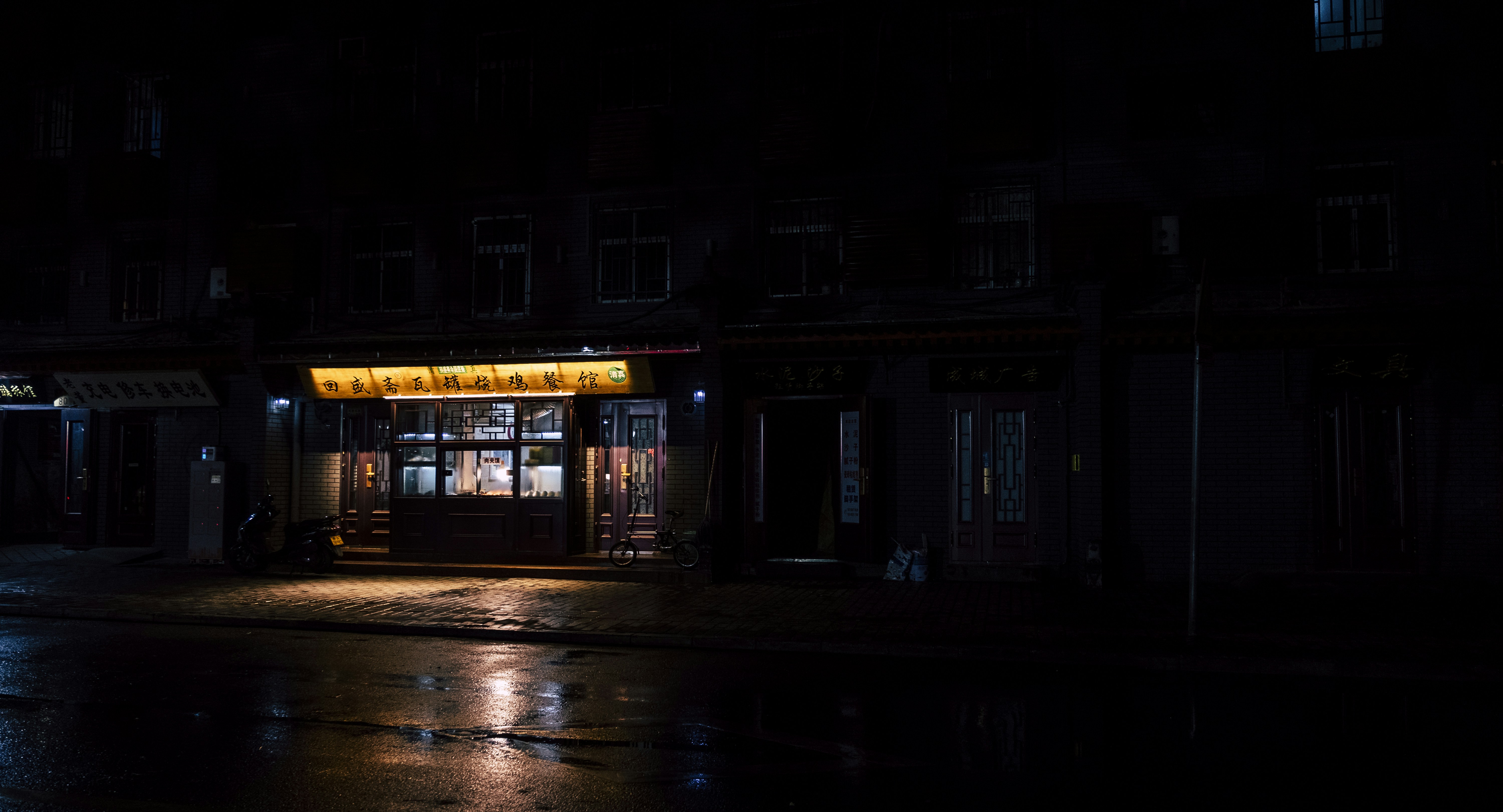 A small mysterious shop glowing at night on a quiet street, warm lights, cinematic and hopeful mood