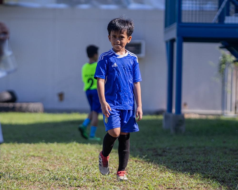 a young boy in a blue uniform playing soccer