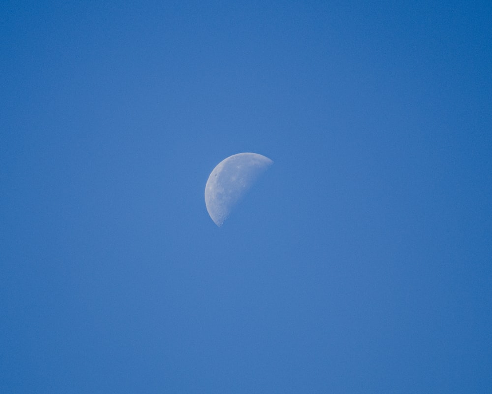 a half moon in a clear blue sky