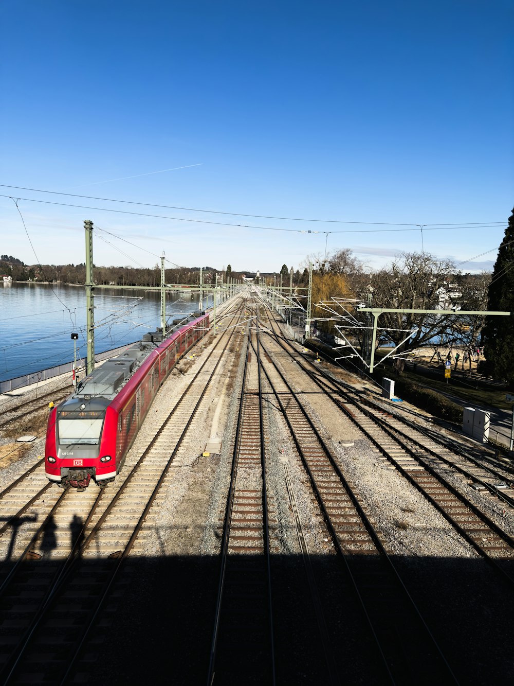 a red train traveling down train tracks next to a body of water