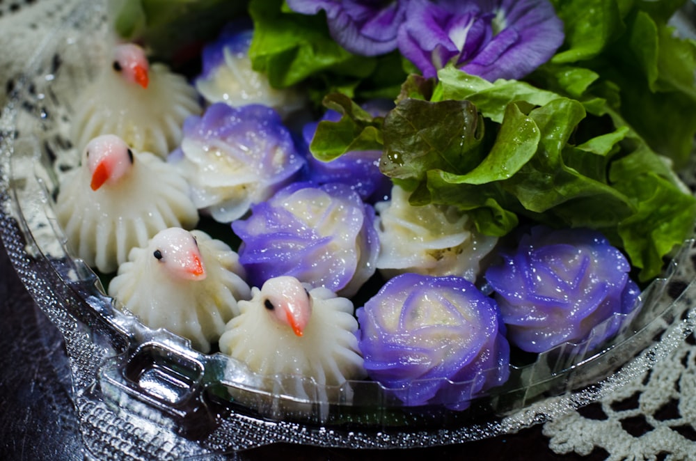 a bowl filled with purple flowers and green leaves