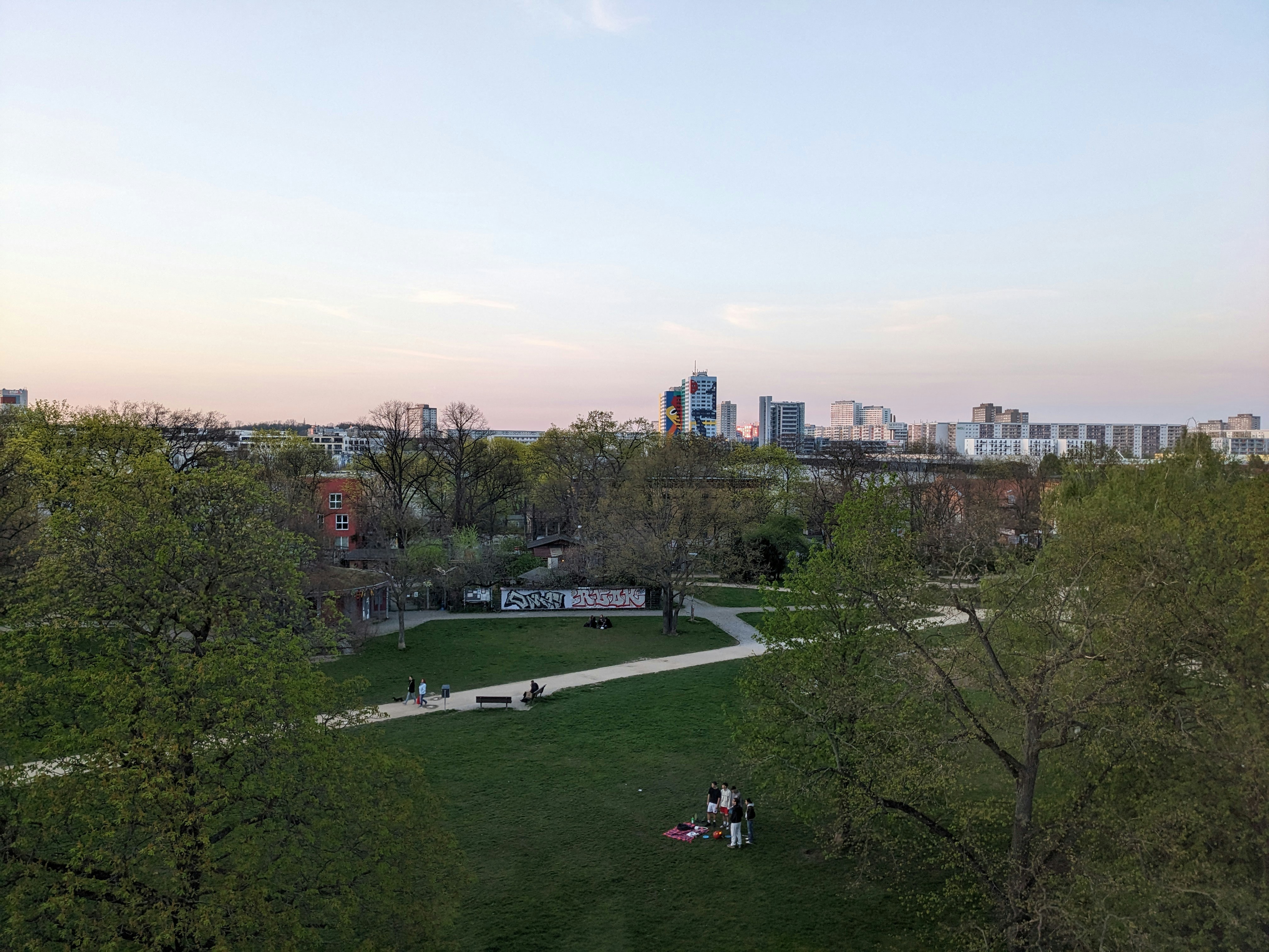a group of people sitting on top of a lush green field, 