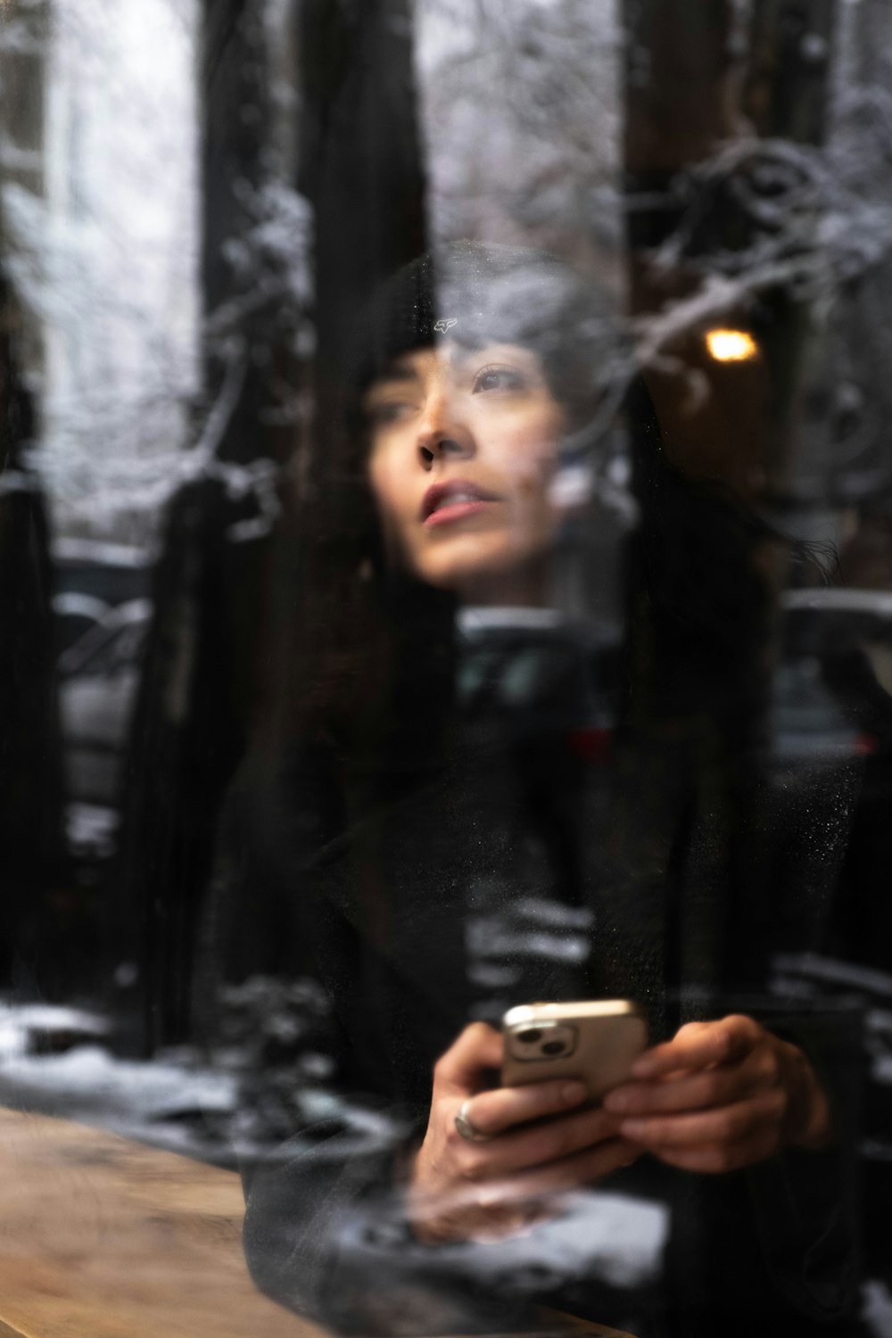 a woman looking at her cell phone through a window
