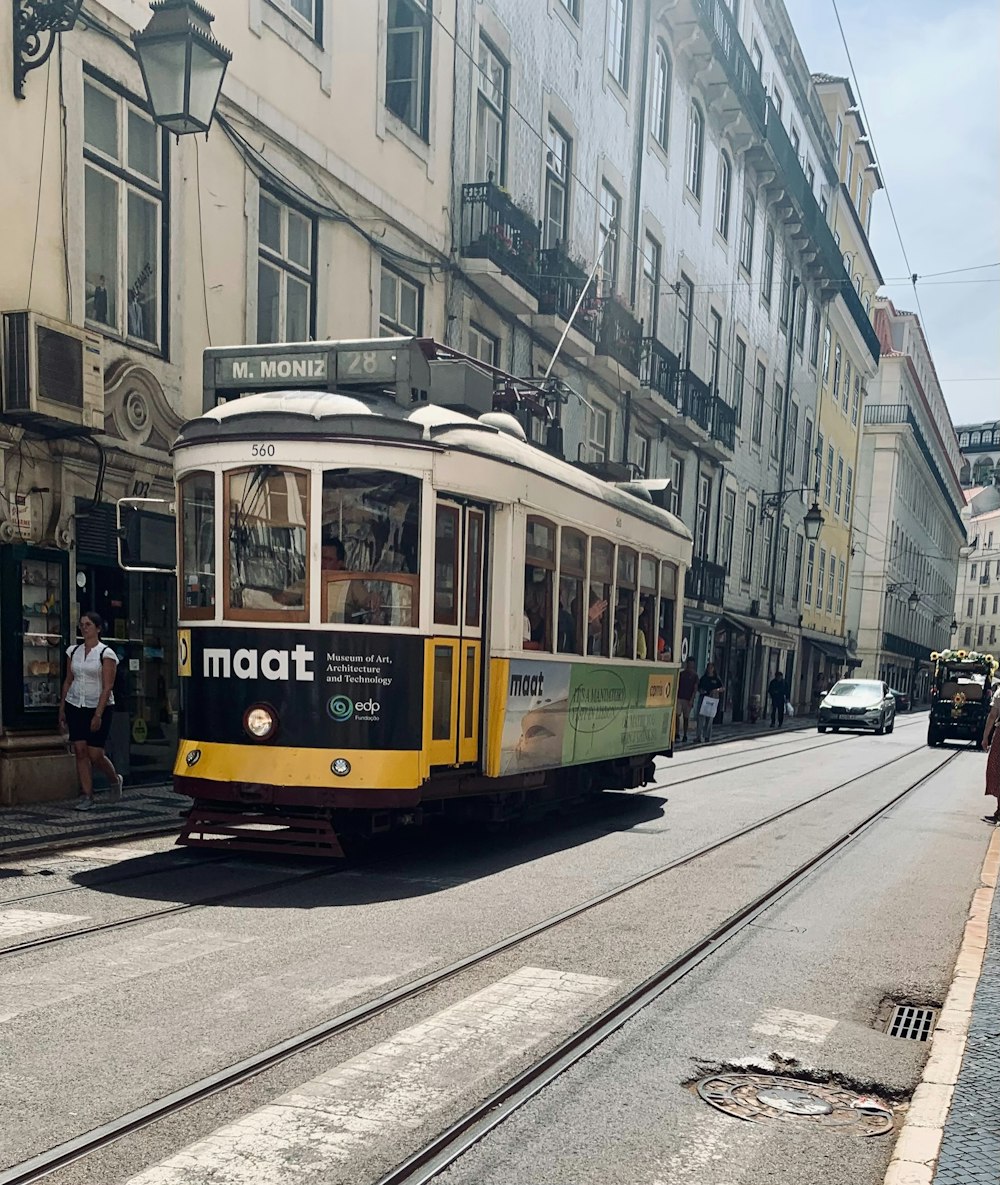 a yellow and green trolley car traveling down a street