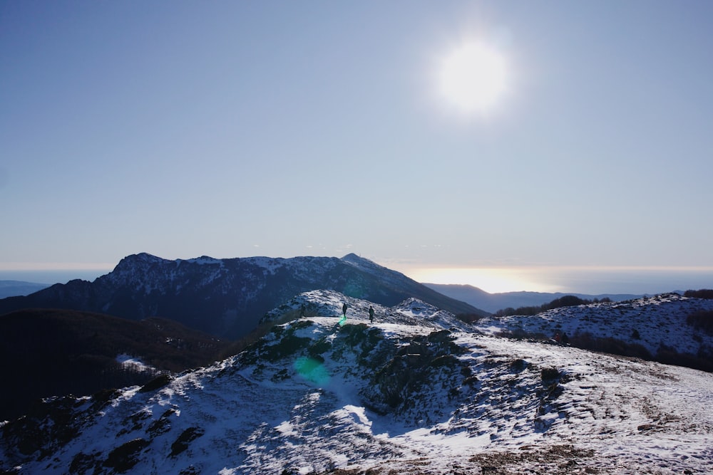 the sun is shining over a snowy mountain