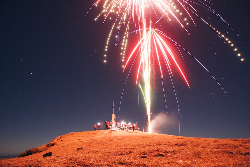 fireworks are lit up in the sky above a hill