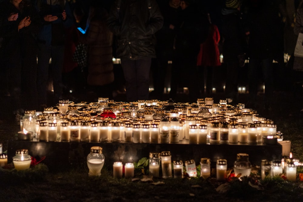 um grupo de pessoas em pé ao redor de um monte de velas acesas