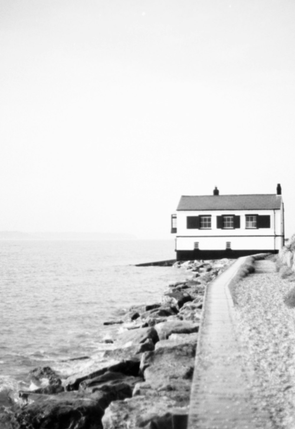 a black and white photo of a house by the water