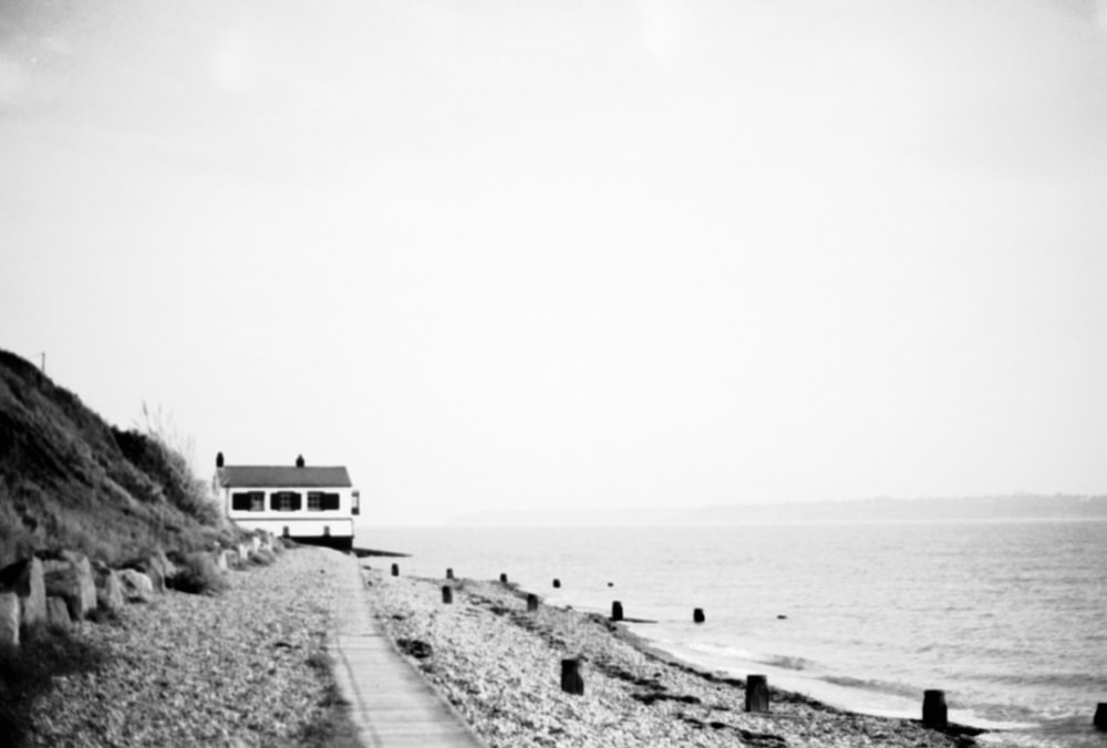 a black and white photo of a house on the beach