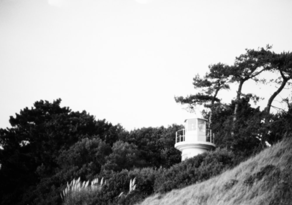 a black and white photo of a lighthouse on a hill
