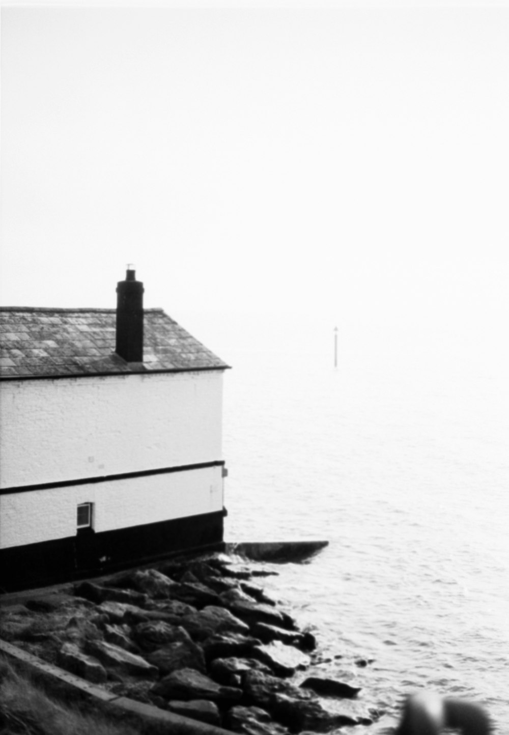 a black and white photo of a house by the water