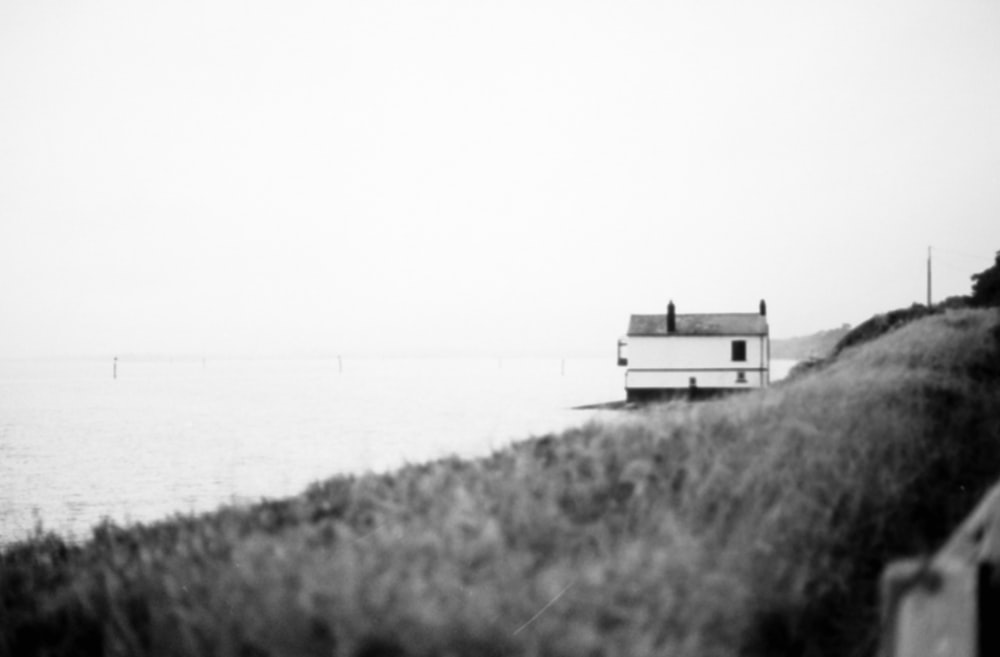 a black and white photo of a house by the water
