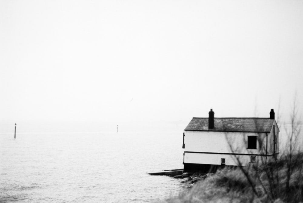 a black and white photo of a house by the water