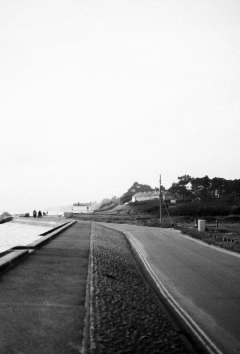 a black and white photo of a street next to a body of water