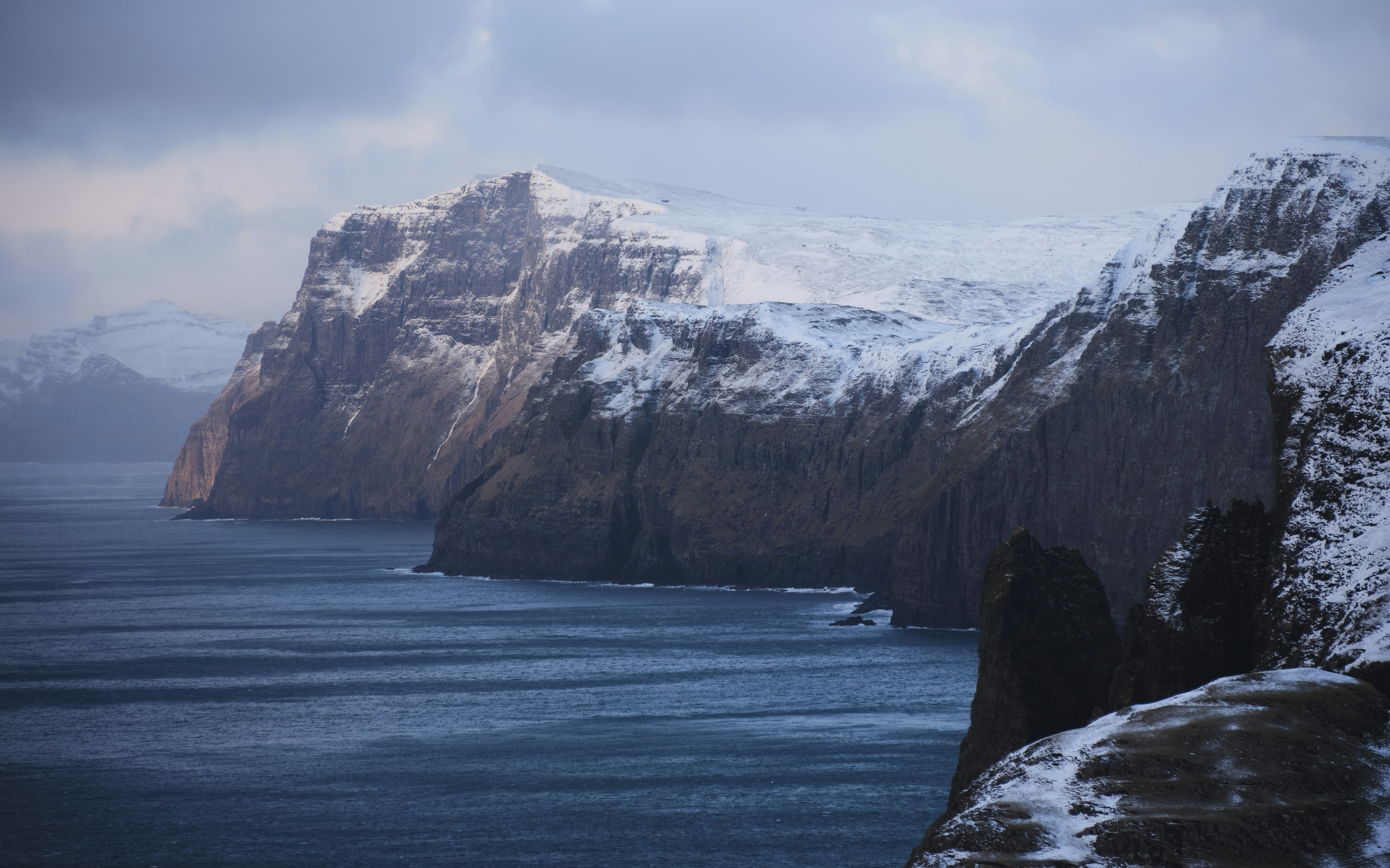 a snowy mountain with a body of water in the foreground, 