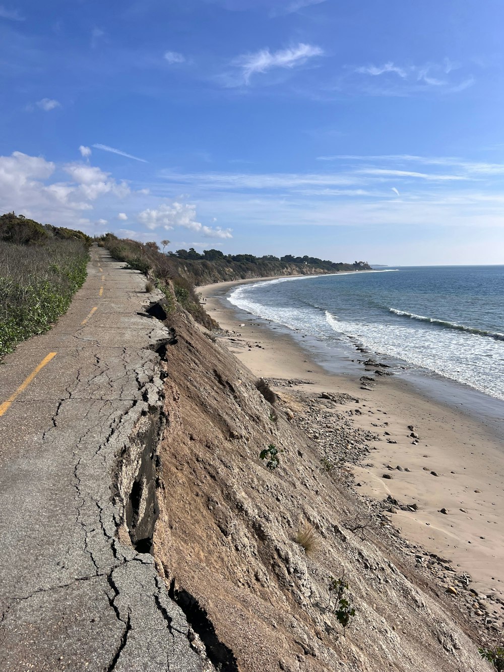 a large crack in the side of a road next to the ocean