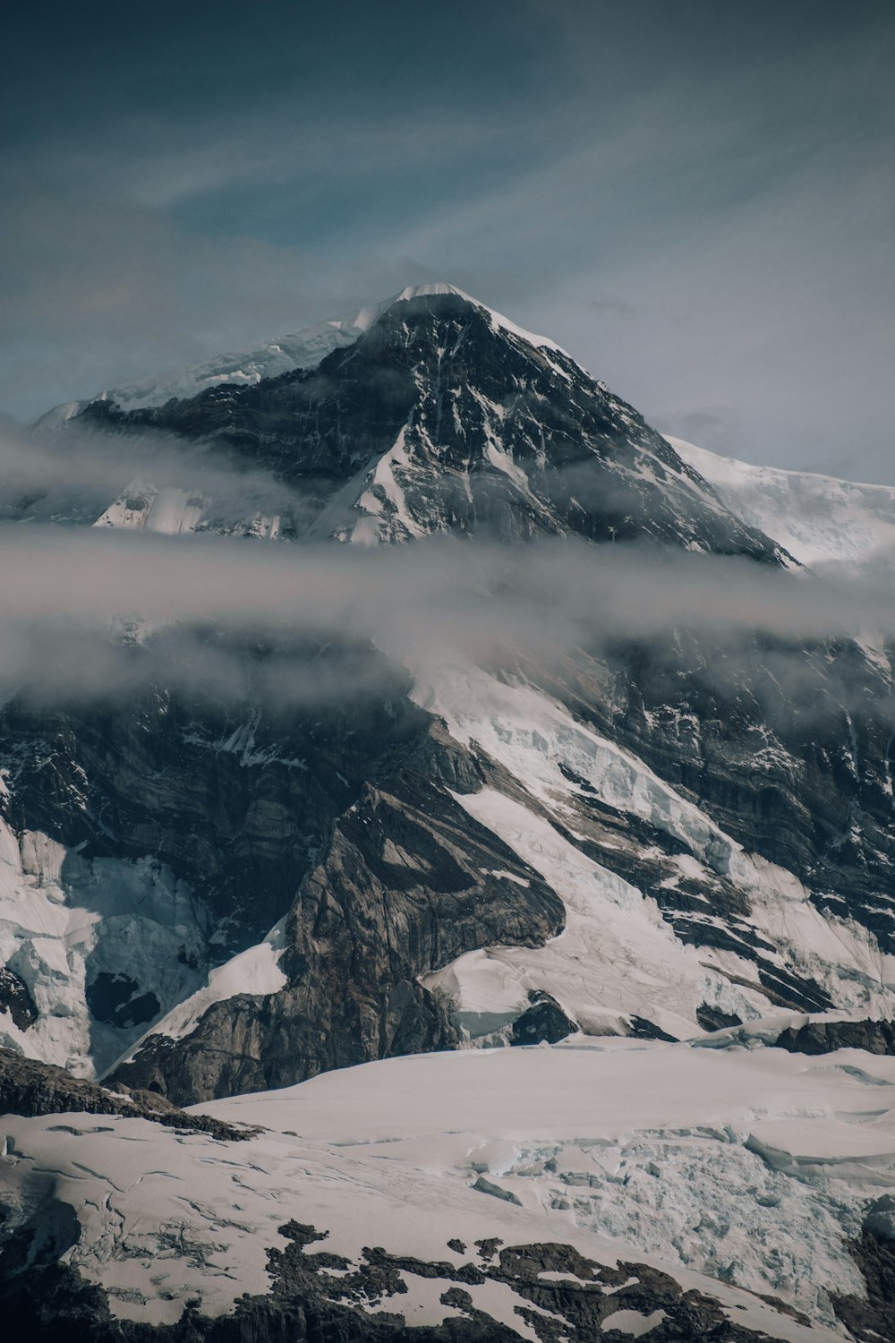 a mountain covered in snow under a cloudy sky