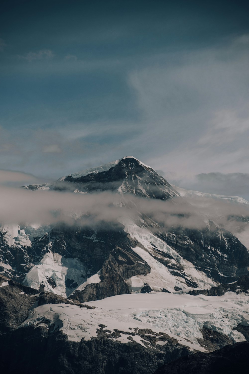 a mountain covered in snow under a cloudy sky