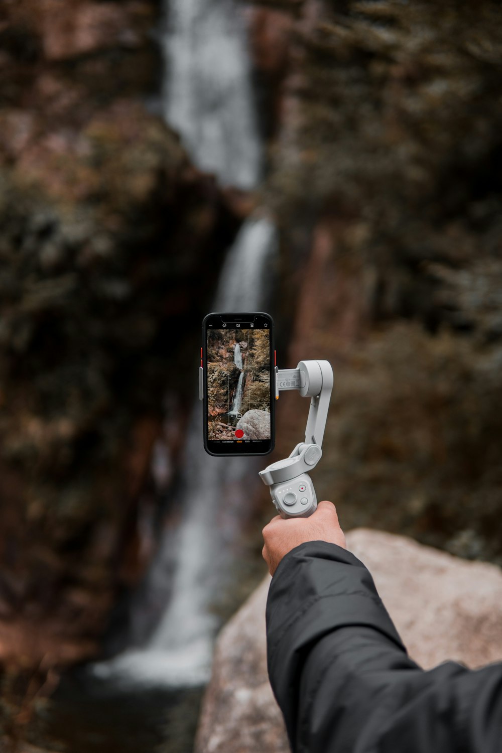 携帯電話で滝の写真を撮る人