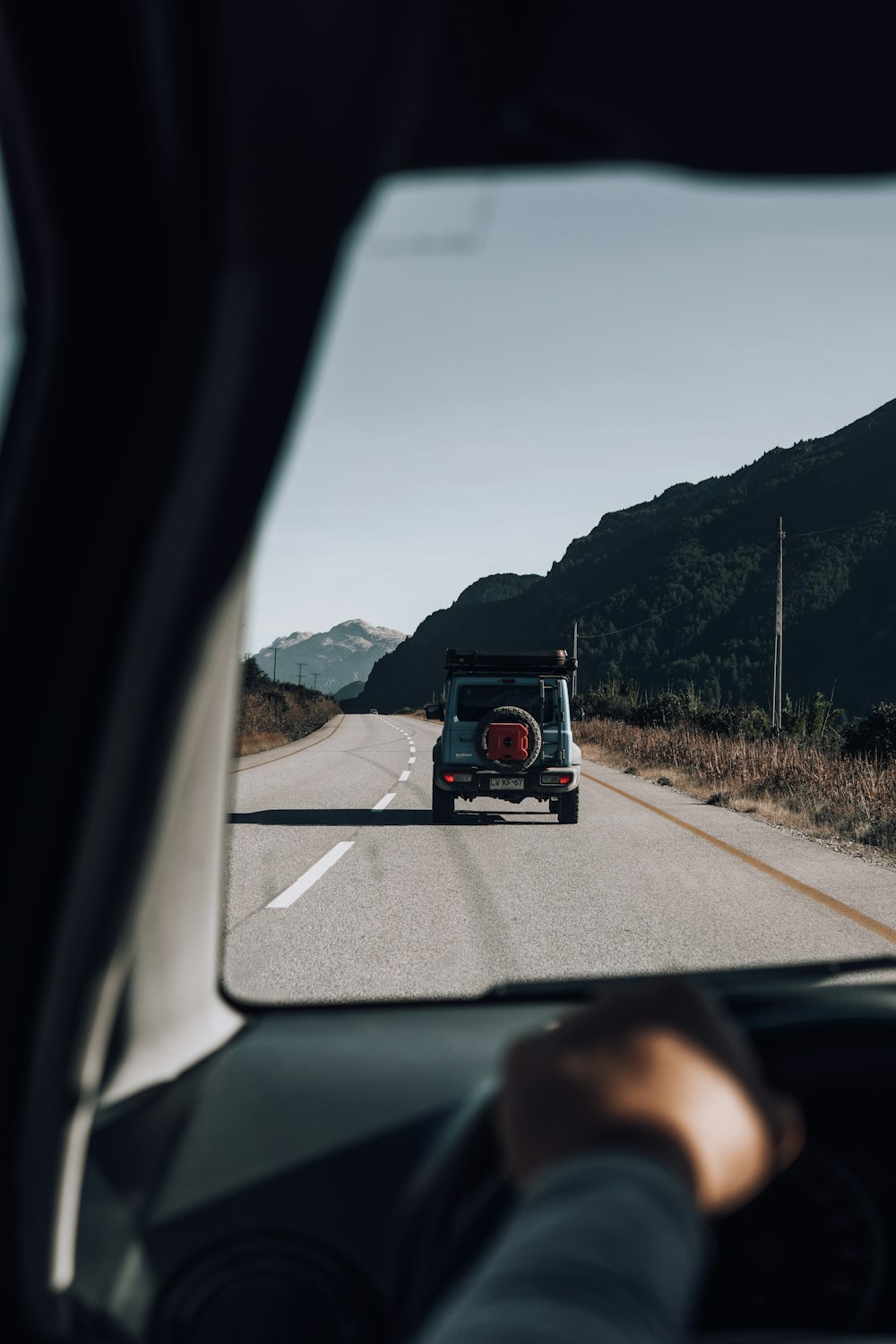 a car driving down a road with mountains in the background