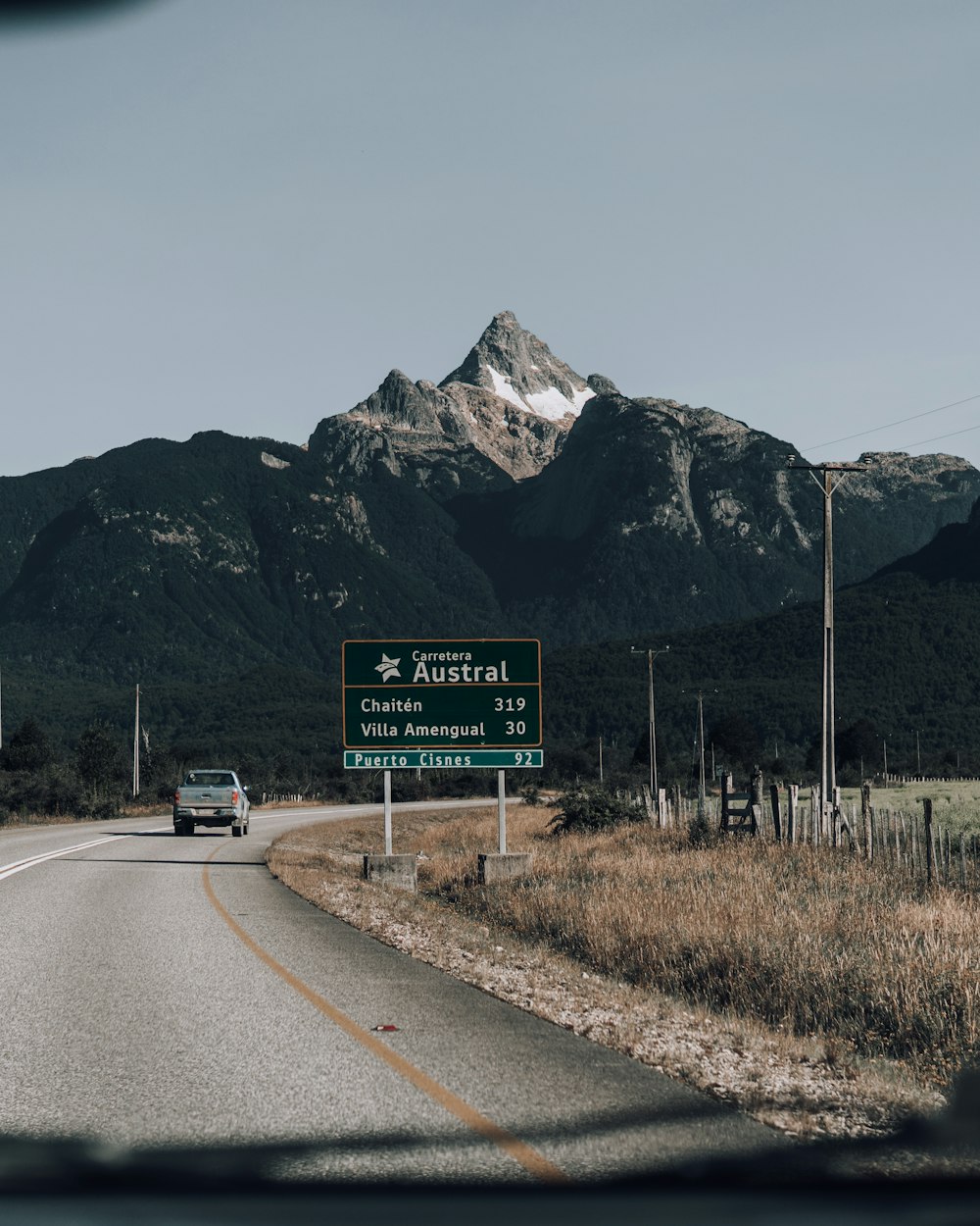 a car driving down a road with a mountain in the background