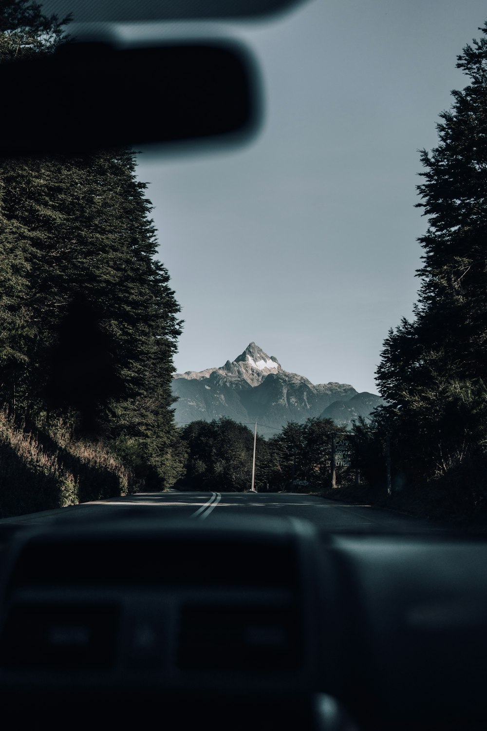 a car driving down a road with a mountain in the background