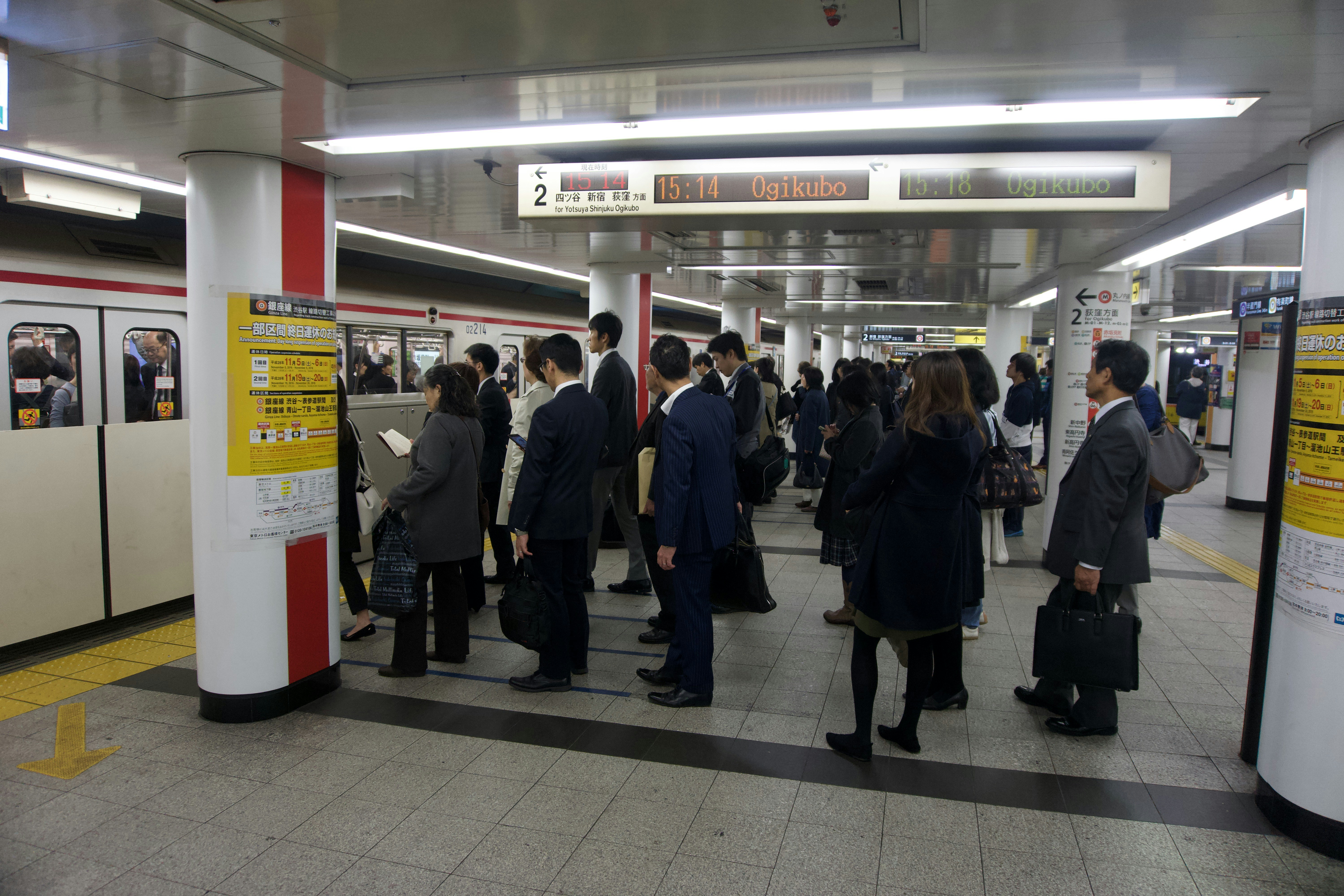 a group of people standing in a subway station, 