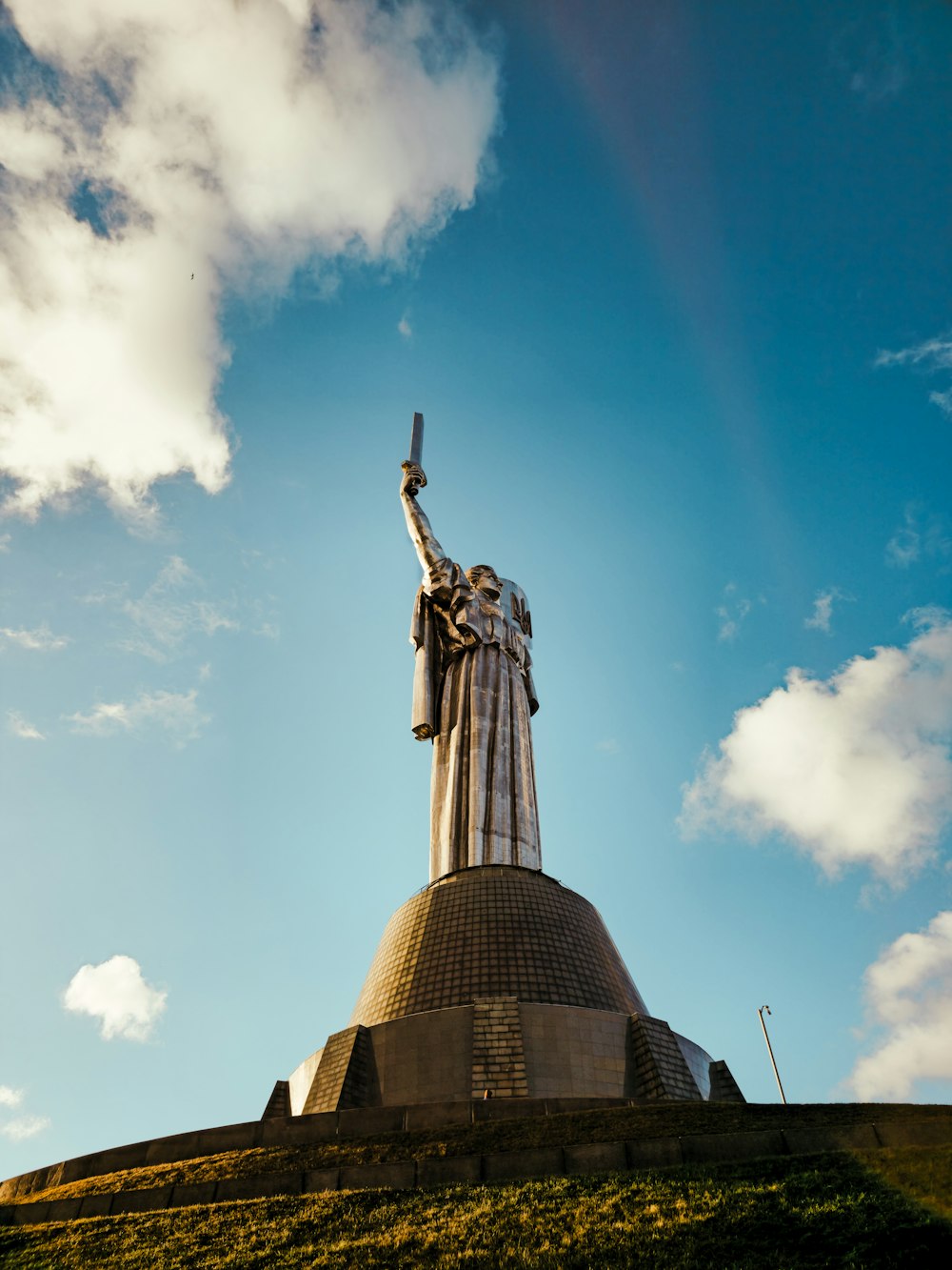 a statue of a woman holding a cross on top of a hill