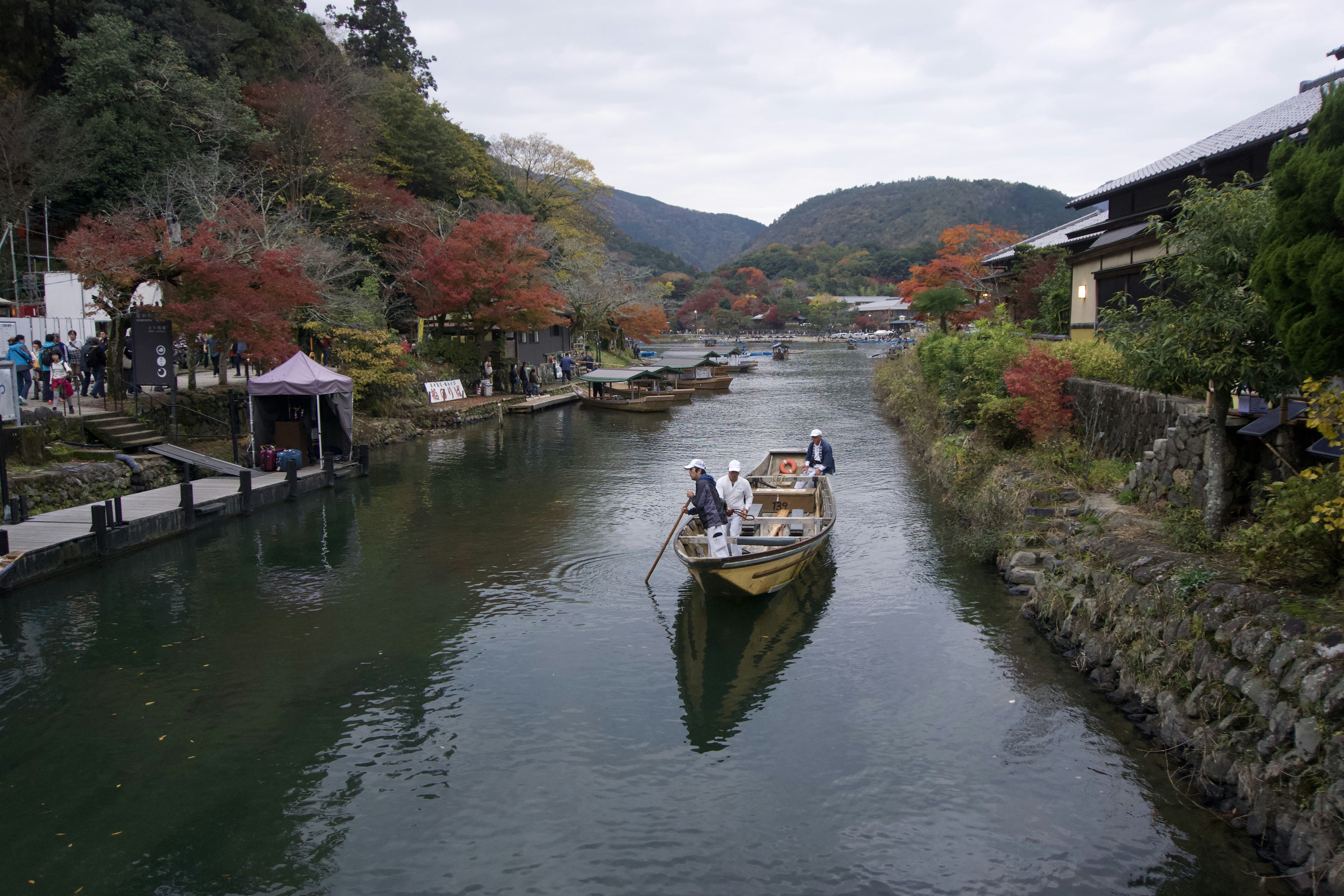 a boat traveling down a river next to a lush green hillside