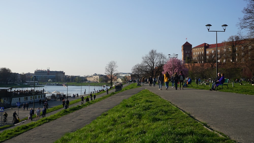 a group of people walking down a path next to a river