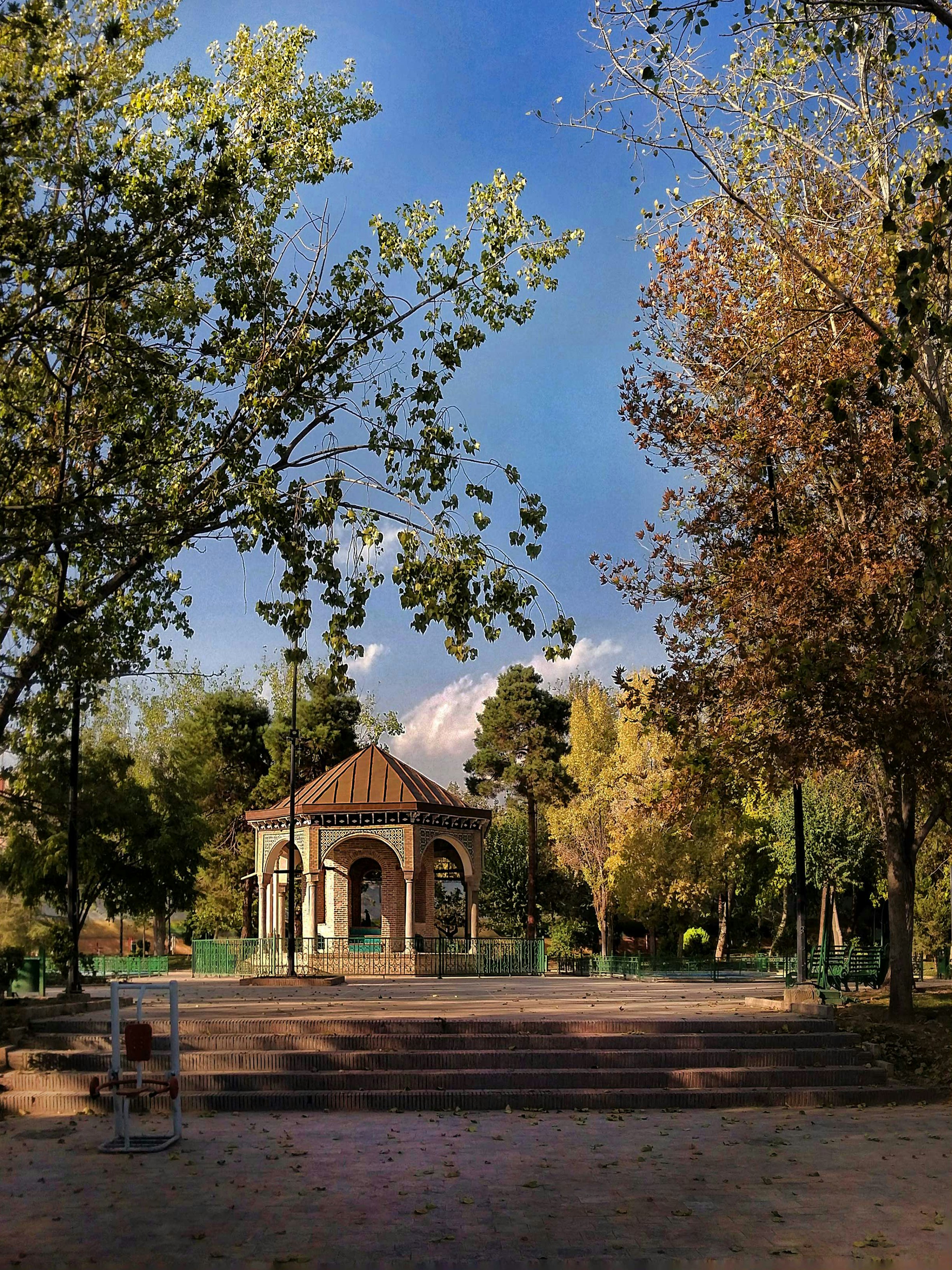a gazebo in the middle of a park surrounded by trees