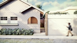 a person walking past a house with a white fence